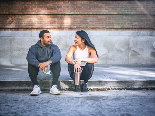 Two people sitting on street curb chatting